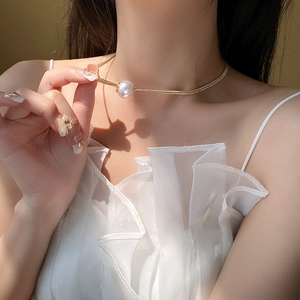 Macro detail of elegant gold plated snake chain with a large lustrous white pearl pendant