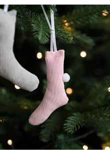 Detailed close-up of a pink knitted mini Christmas stocking with white pompom and hanging loop