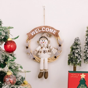 Close-up of Christmas wreath with plush snowman and wooden Welcome sign hanging on wall