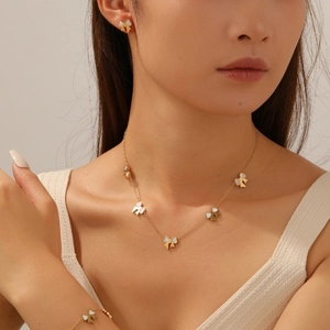Close-up of gold-plated bow jewelry set with white mother-of-pearl inlay worn by model