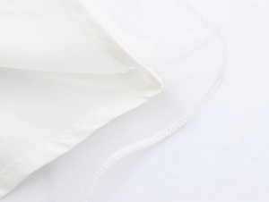 Detailansicht des weißen Mesh-Gewebes und der präzisen Nähte am eleganten Perlenkleid