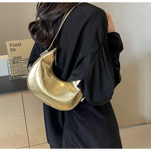 Detail of metallic gold crescent bag showing shiny leather texture and silver zipper