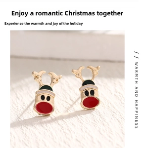Macro view of gold-plated reindeer stud earrings with festive red and green enamel coating