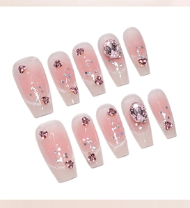 Detailed view of pink gradient long coffin press-on nails with heart rhinestones
