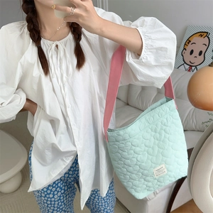 Detail showing heart-quilted texture and pink strap on mint green shoulder bag