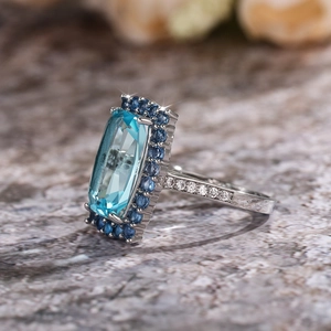 Vue latérale détaillée de la bague en zircon bleu avec monture argentée et petits diamants