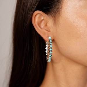Detail view of turquoise beads set in a silver hoop earring worn by a model