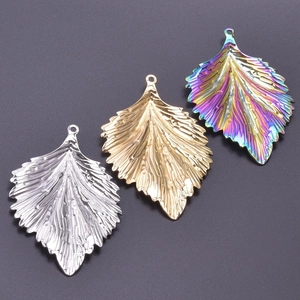 Macro view of leaf-shaped stainless steel charms in silver, gold and rainbow finishes