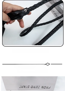 Detail of hand-woven black leather whip with metallic rivets and wrist strap for costumes