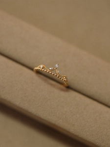 Detailed close-up of a 18K gold crown ring with sparkling zircons on beige velvet