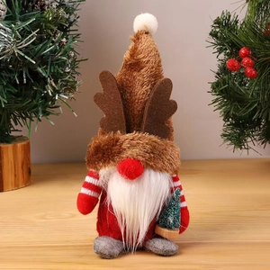 Close-up of Christmas gnome plush with reindeer antlers holding a mini snowy pine tree