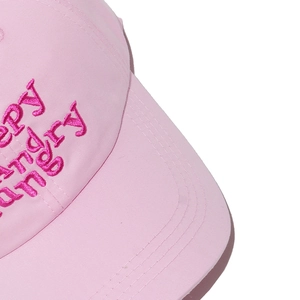 Détail d'une casquette en coton rose avec broderie HAPPY HANGRY et coutures soignées