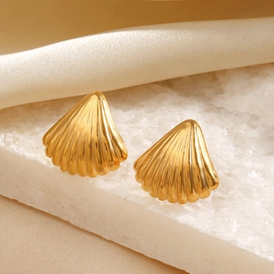 Elegant gold shell stud earrings on stone slab with soft silk background for beach style