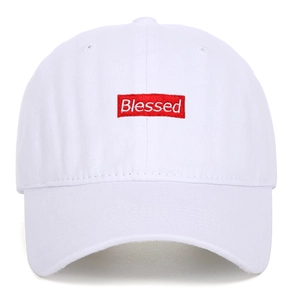 Detailed close-up of white blessed embroidery on a red patch for cotton baseball caps