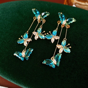 Détail de boucles d'oreilles papillon dorées avec zircon bleu et pampille sur velours