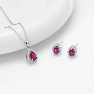 Detailed view of pear-cut red ruby pendant necklace and matching silver diamond earrings