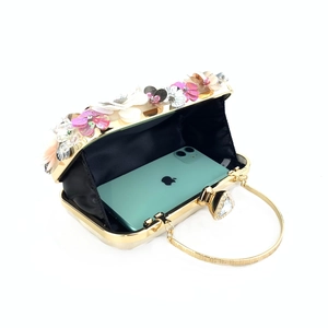 Detail view of floral evening clutch bag showing spacious interior with a smartphone