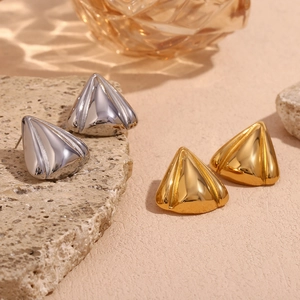 Close-up of geometric 18K gold and silver plated triangle earrings on textured stone