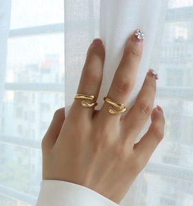 Detail shot of gold hugging hands open ring shown on finger with soft window lighting