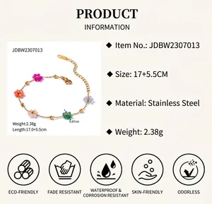 Détail macro du bracelet en acier doré avec cinq breloques fleurs colorées
