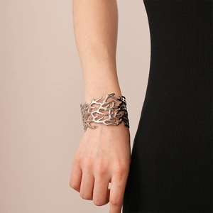 Detail of silver textured branch cuff bracelet with a wide hollowed coral design