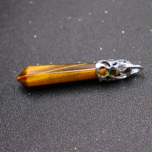 Hexagonal tiger eye stone pendant with polished silver alloy clasp on black surface