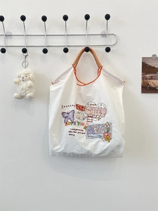 White graffiti canvas tote bag featuring butterfly prints and a plush sheep pendant detail