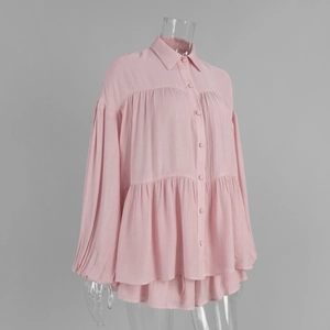 Detail of pink lantern sleeve shirt featuring textured fabric and layered ruffle hemline