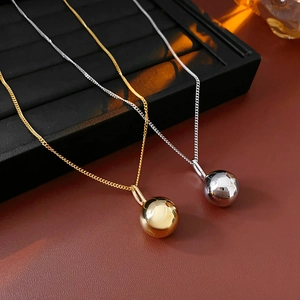 Detail shot of gold and silver polished metal ball pendants on delicate chains