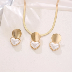 Elegant gold snake chain jewelry set featuring textured discs and heart pearl charms