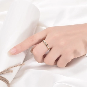 Close-up of golden spinning ring with crystal pavé on hand with white silk background