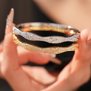 Detailed view of gold and silver plated bangles featuring a quilted zircon cross pattern