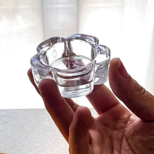 Hand holding flower-shaped glass candle holder with transparent petal design for home decor