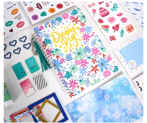 Macro view of blue floral spiral notebook with Dream Big text and stationery accessories