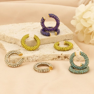 Macro shot of colorful zircon-encrusted titanium steel C-shaped ear cuffs on stone background