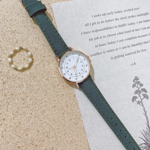 Detail van een dameshorloge met groene lederen band, gouden rand en een parelring