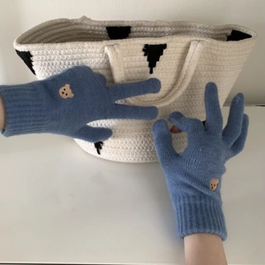 Close-up of blue knitted gloves featuring cute brown bear embroidery and ribbed cuffs
