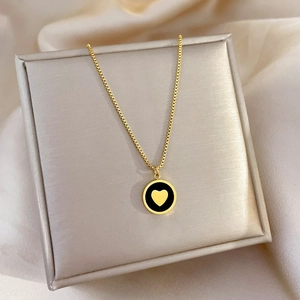 Detailed close-up of a golden heart pendant on a black enamel circular necklace base