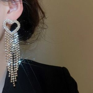 Long golden heart tassel earrings with sparkling rhinestones worn by a model