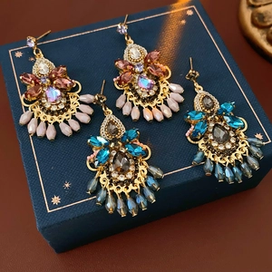 Detailed shot of two pairs of Baroque-style crystal earrings on a blue star-patterned box