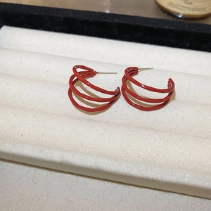 Detailed view of red geometric triple-layered curved earrings on a jewelry display tray
