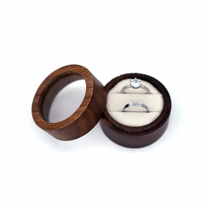Macro detail of a round walnut wood ring box with a glass lid and white velvet interior
