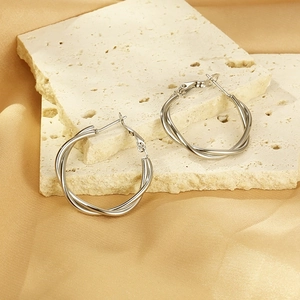 Silver twisted rope hoop earrings made of titanium steel on elegant silk background