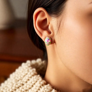 Detail of Easter egg-shaped striped earrings with crystals on a woman's ear