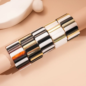 Macro detail of acrylic geometric bangles featuring amber and gold resin block layers