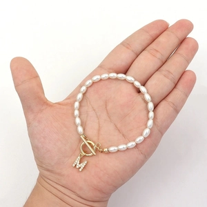 Elegant pearl bracelet with gold OT clasp and zircon M initial pendant on palm