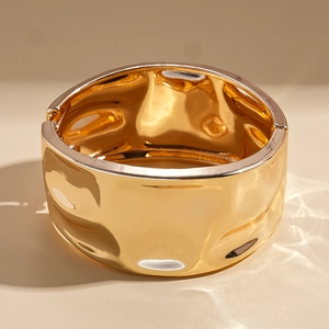 Polished golden wide cuff bracelet with a unique hammered texture and a minimalist design