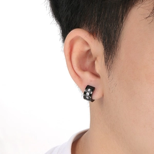 Macro detail of black titanium C-shaped earring featuring three white cubic zirconia stones
