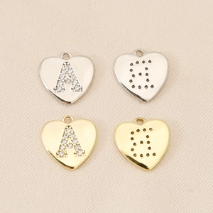 Détail macro de pendentifs cœur en or 18 carats et argent avec lettres A et B serties