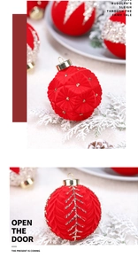 Detail of red velvet Christmas balls with gold geometric patterns on snowy pine branches